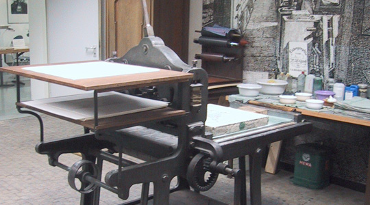 alte Steindruckpresse, im Hintergrund ein Arbeitstisch